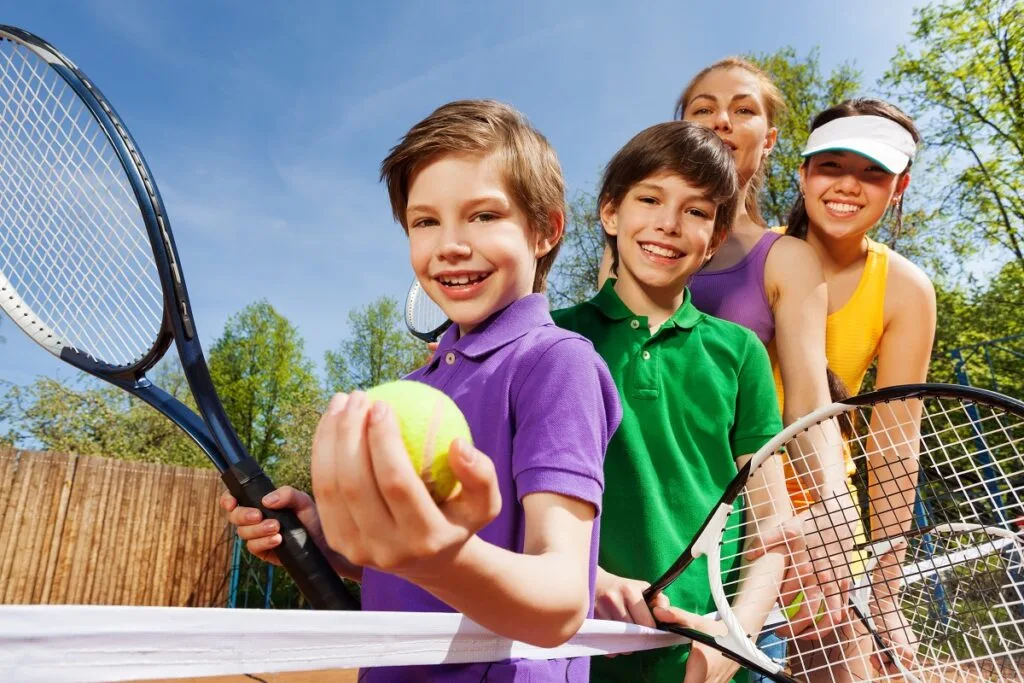 Picture of children holding a tennis ball and racquets, ready to play tennis.